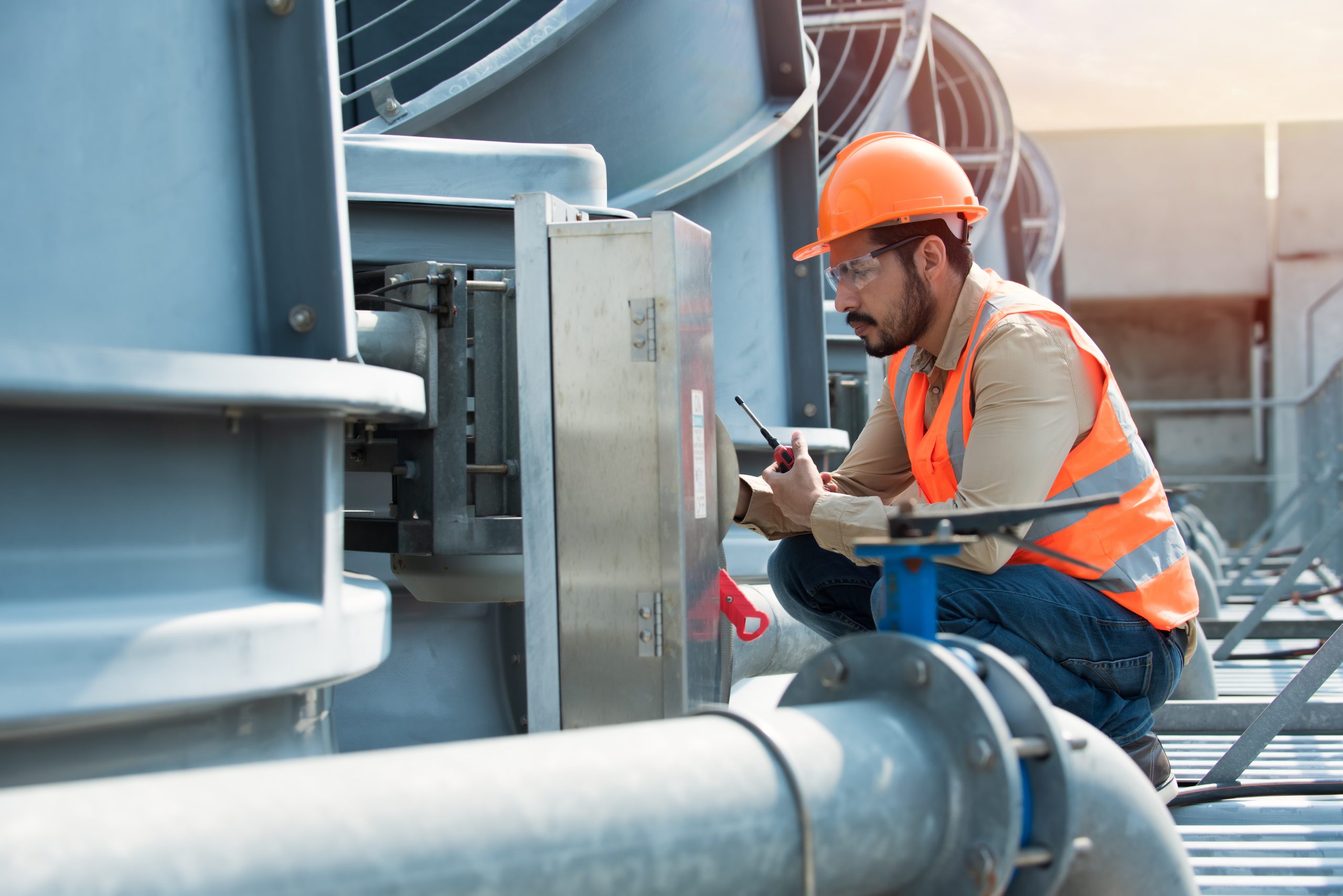 A Master Systems Integrator checking the interconnected HVAC components on top of an office building.