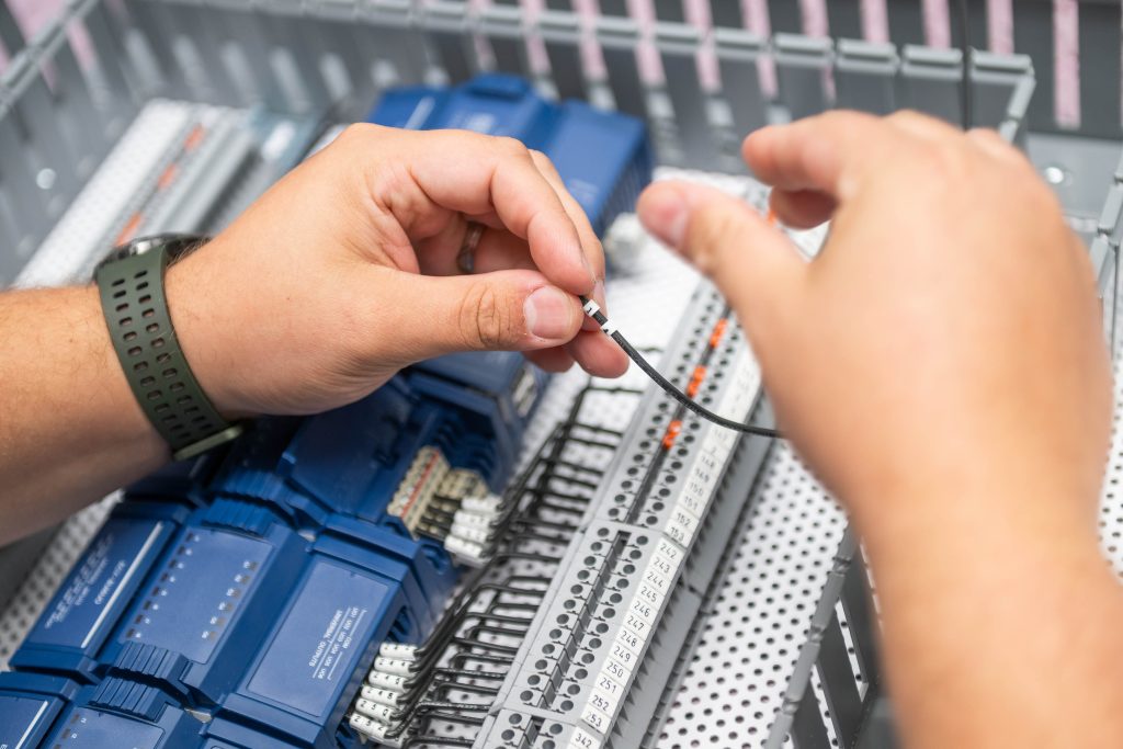 A technician connects wires as part of a BAS integration.