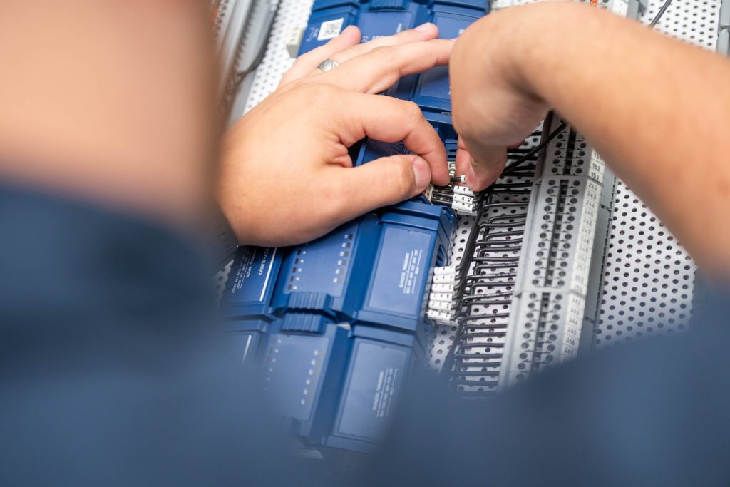 A close-up on the hand s of a Conexus Controls Technician as he installs a BAS Upgrade