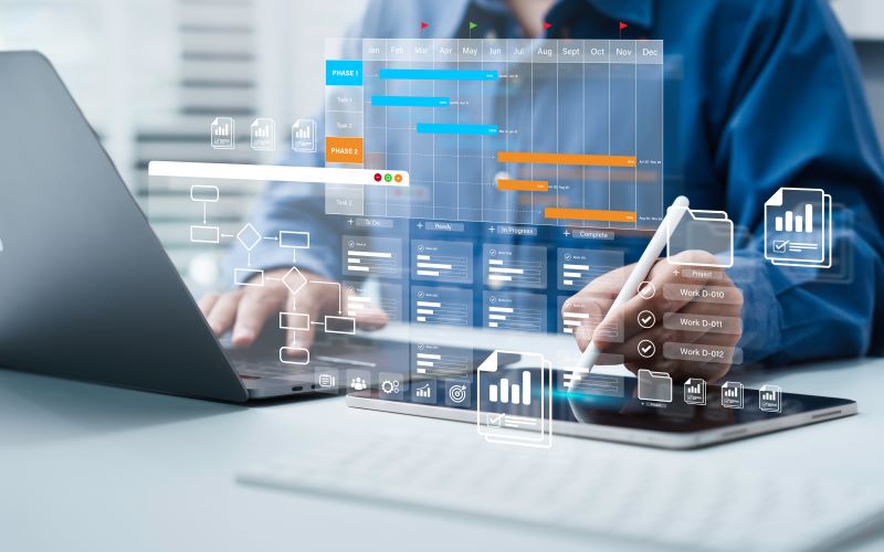 Project manager works on computer and tablet to schedule a company's projects.
